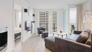 Una sala de estar moderna con un televisor de pantalla plana, un sofá gris y un comedor con mesa y sillas.