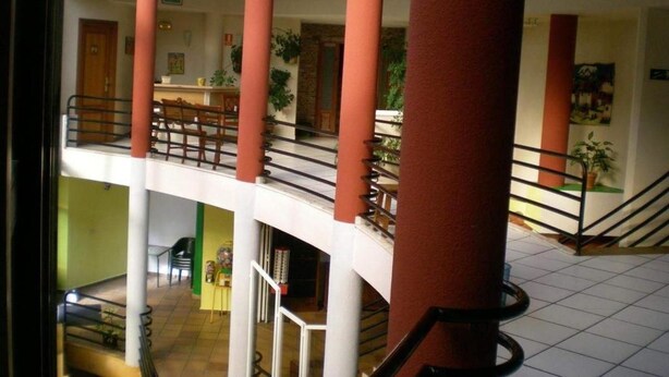 Un intérieur à plusieurs niveaux doté d’un atrium central, de colonnes et d’un escalier.