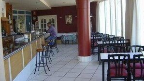 Un restaurant doté d’un bar, d’un sol carrelé et de plusieurs tables et chaises.