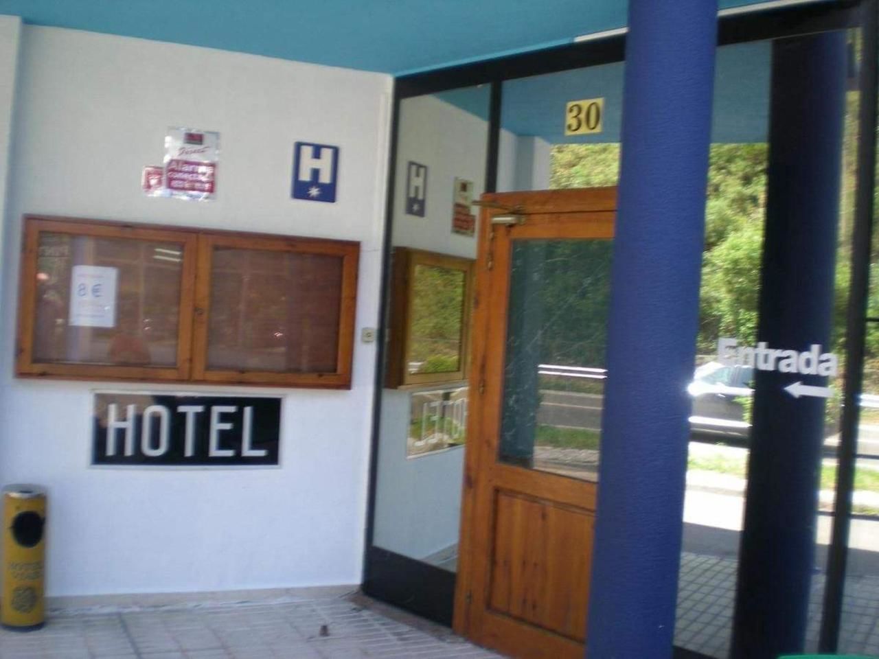 Entrada de un hotel con una puerta de madera, un cartel que dice 