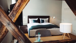 A hotel room with a bed, bedside table, lamp, and a view through a wooden structure. - Hotel Zum Schwan (Wanfried)