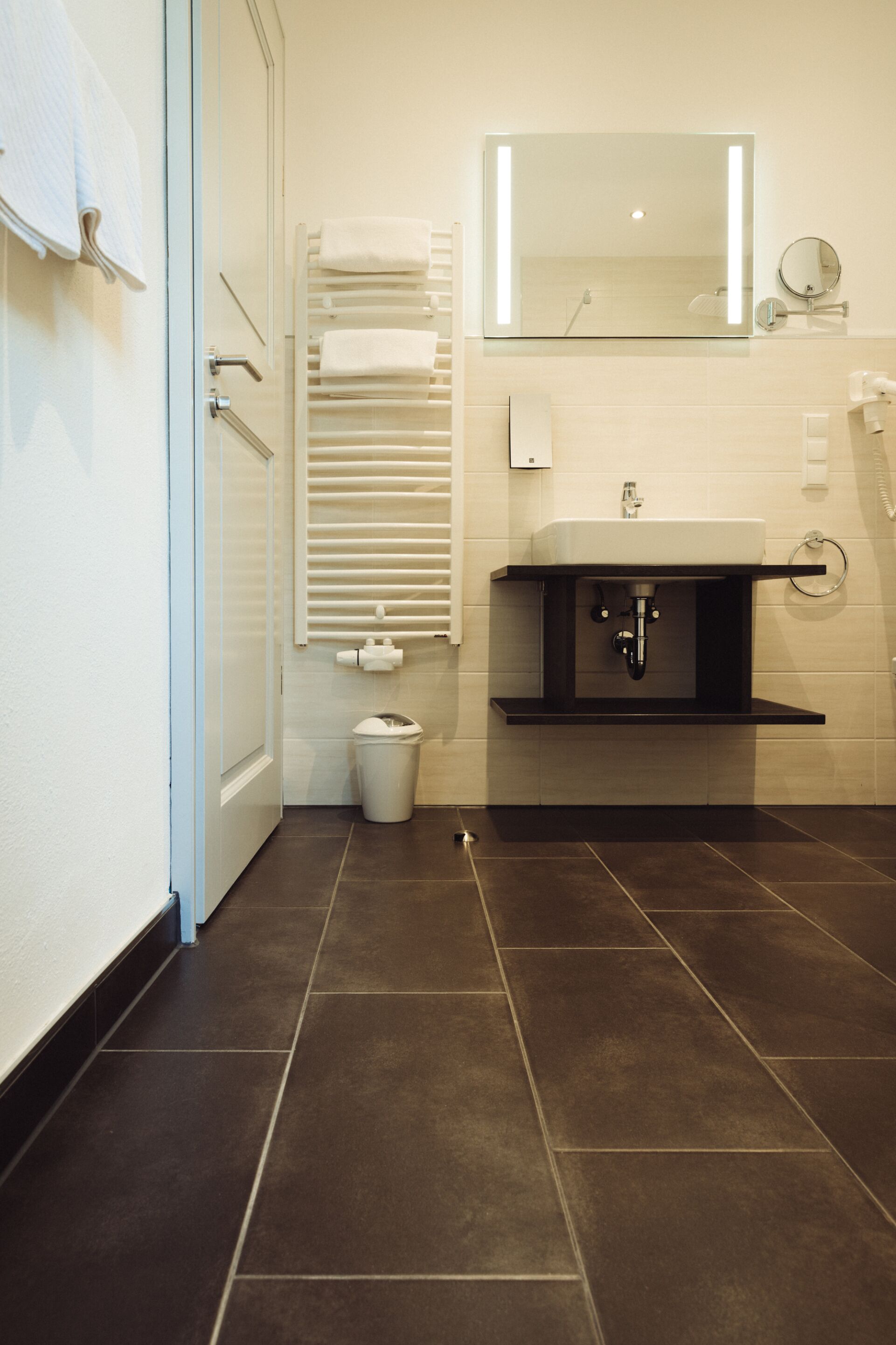 A bathroom with a white sink, a mirror, a towel rack, and a toilet.