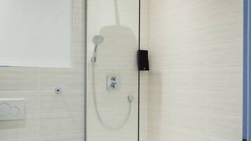 A modern bathroom with a glass-enclosed shower, a white toilet, and a tiled floor.