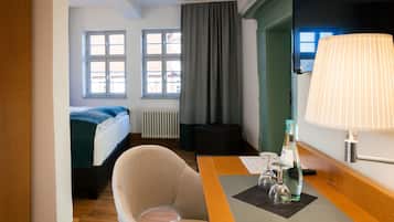 Ein Hotelzimmer mit einem Bett, einem Sessel, einem Tisch mit Lampe und einem Fenster mit Vorhängen.