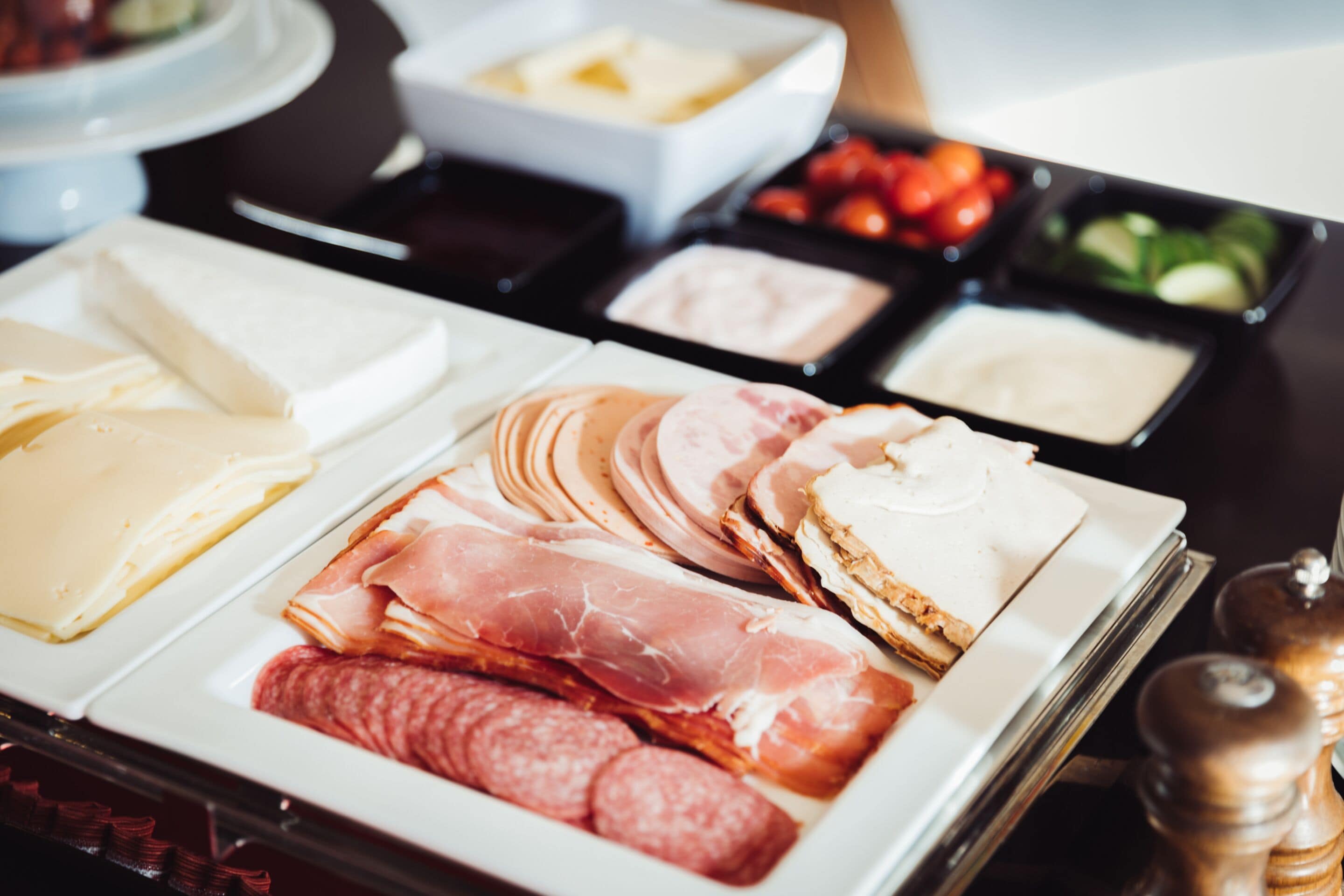 Eine Auswahl an Käse, Wurstwaren und Beilagen auf einer Platte.