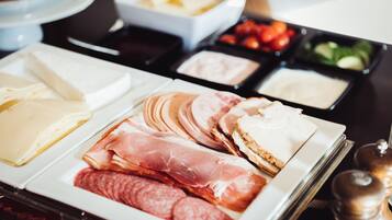 Eine Auswahl an Käse, Wurstwaren und Beilagen auf einer Platte.