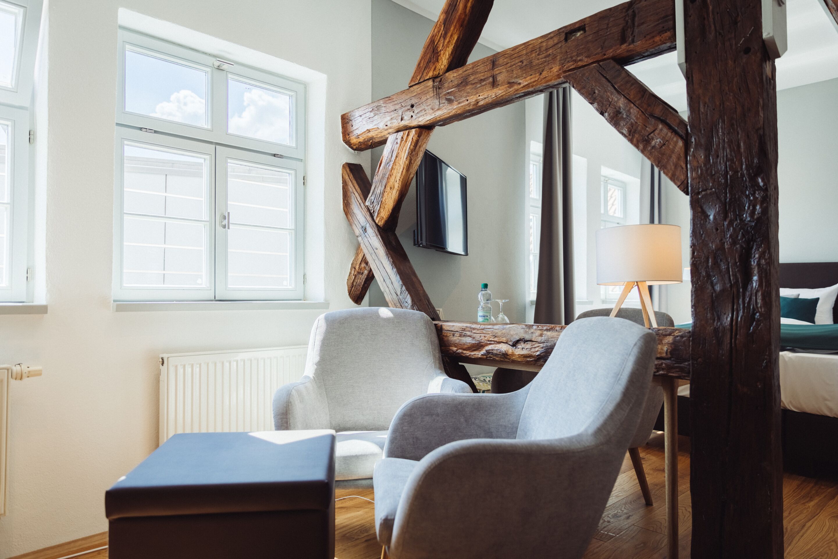 Una habitación con techo de madera rústica, una cama, un escritorio con lámpara y dos sillones.