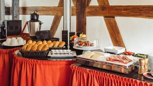 A buffet table with various food items, including bread, cheese, and meats, set against a rustic wooden backdrop. - Hotel Zum Schwan (Wanfried)