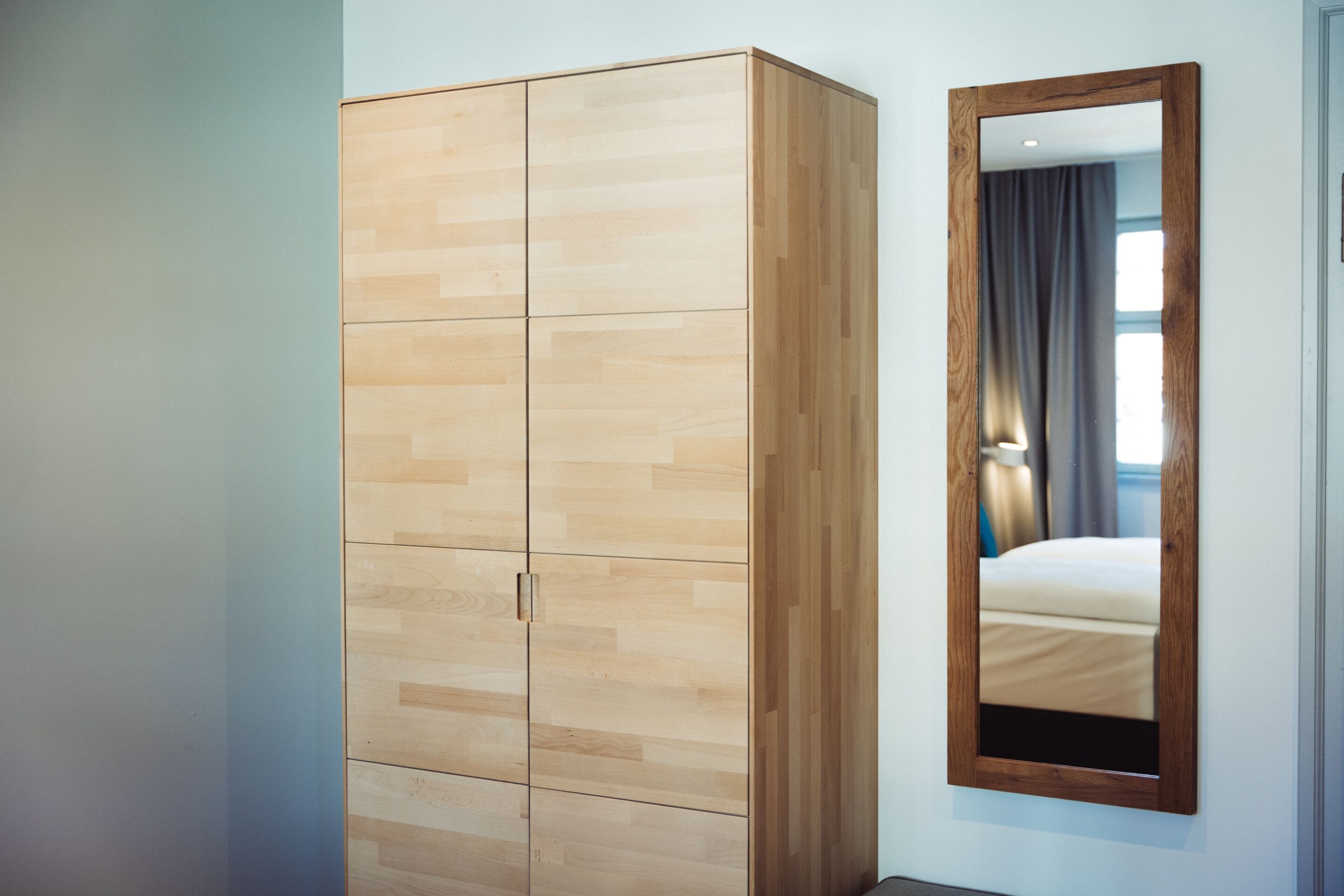 Une chambre à coucher avec une armoire en bois, un miroir et un lit.