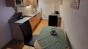 Une cuisine compacte équipée d’un four à micro-ondes, d’un évier et d’un petit coin repas avec une table et une chaise.