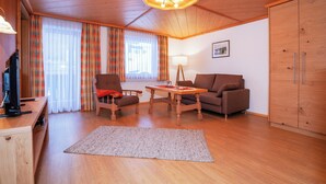 Un salon chaleureux avec un plancher en bois, un plafond en bois, une table à manger avec des chaises, un canapé, un téléviseur et un meuble.