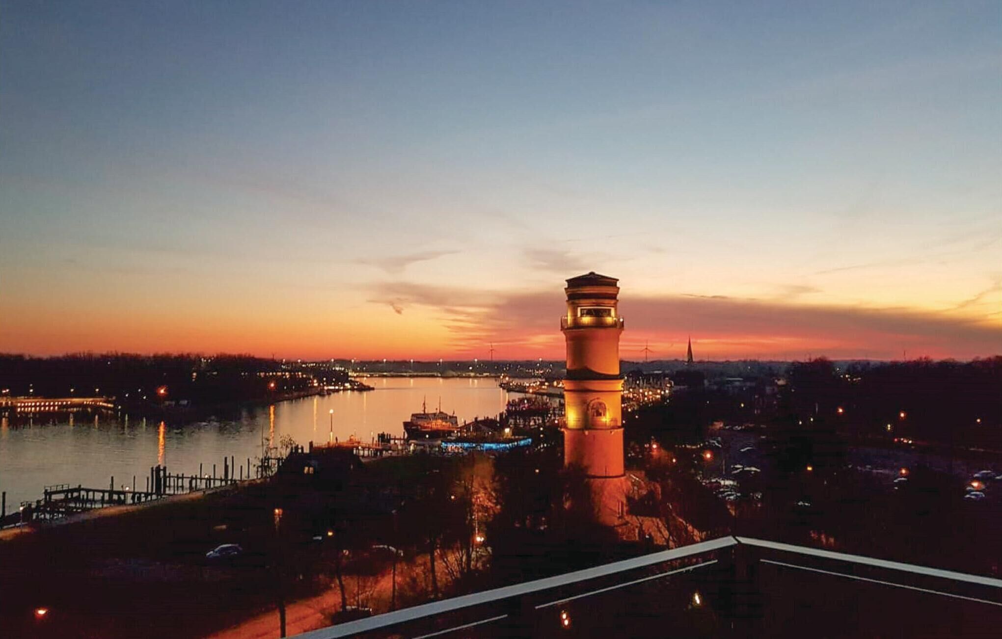 A sunset view from a high vantage point overlooking a cityscape with a prominent tower and a river.