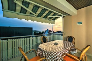 A balcony with a table and chairs, a view of the sunset, and a white fence. - Apartments & Rooms Peranic (Novalja)