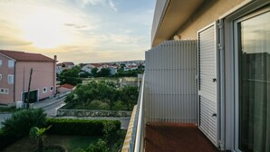 A balcony with a view of a residential area, a white door, and a window.