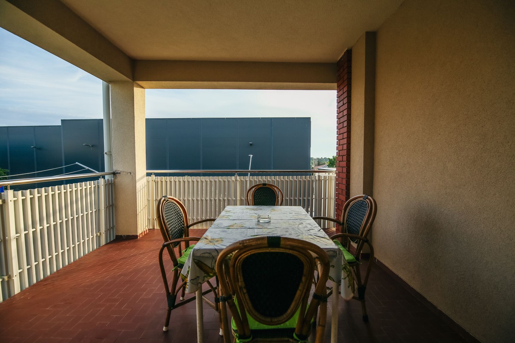 A balcony with a table and chairs, a view of the city, and a building in the background.
