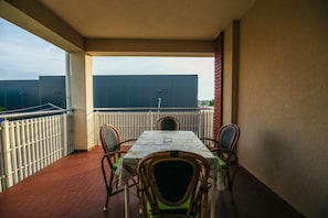 A balcony with a table and chairs, a view of the city, and a building in the background.