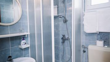 A bathroom with a shower enclosure, a sink, a toilet, and a mirror.