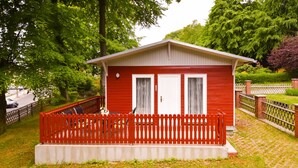Un piccolo edificio rosso con due porte e un portico recintato.