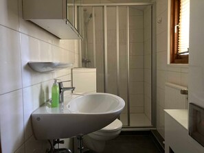 Ein Badezimmer mit weißem Waschbecken, WC und Duschkabine.