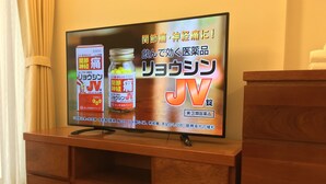 Ein Fernseher auf einem Holzständer mit einer japanischen Werbung.