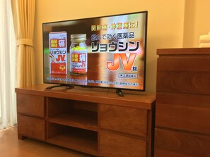 A television on a wooden stand with a Japanese advertisement. - Palmo Serviced Apartment 3 (Hanoi)