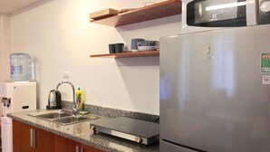 Eine moderne Küche mit einem Edelstahlkühlschrank, einer eingebauten Mikrowelle, einem Wasserspender und einem Wasserkocher.