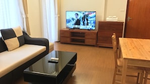 Ein Wohnzimmer mit einer Couch, einem Couchtisch, einem Fernseher und einem Holztisch.
