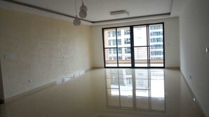 A spacious, empty room with a large sliding glass door leading to a balcony, a ceiling light fixture, and a clean, polished floor. - Kileleshwa Lux Condo (Nairobi)