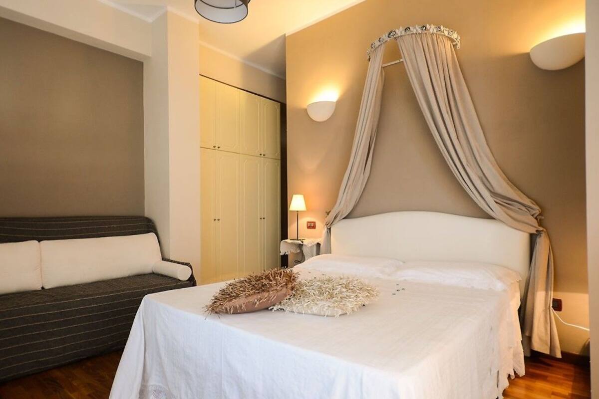 A bedroom with a bed, a sofa, a wardrobe, and a nightstand with a lamp.
