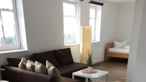 A modern living room with a brown sofa, a white coffee table, and a wooden floor. - Landgasthof Schwabhausen (Schwabhausen)