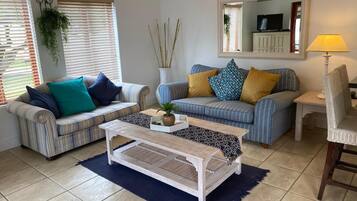 A living room with striped sofas, a coffee table, a lamp, and a TV.