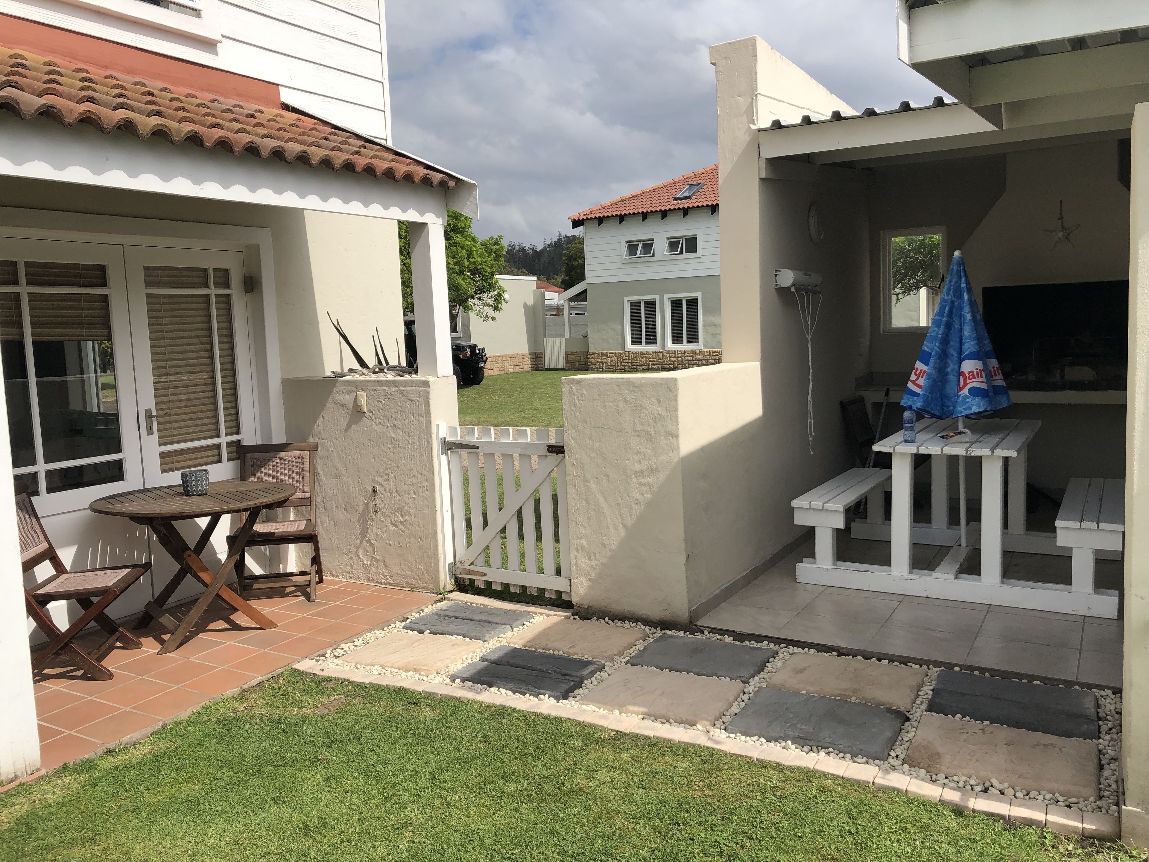 A patio area with a table and chairs, a small garden, and a view of neighboring houses.