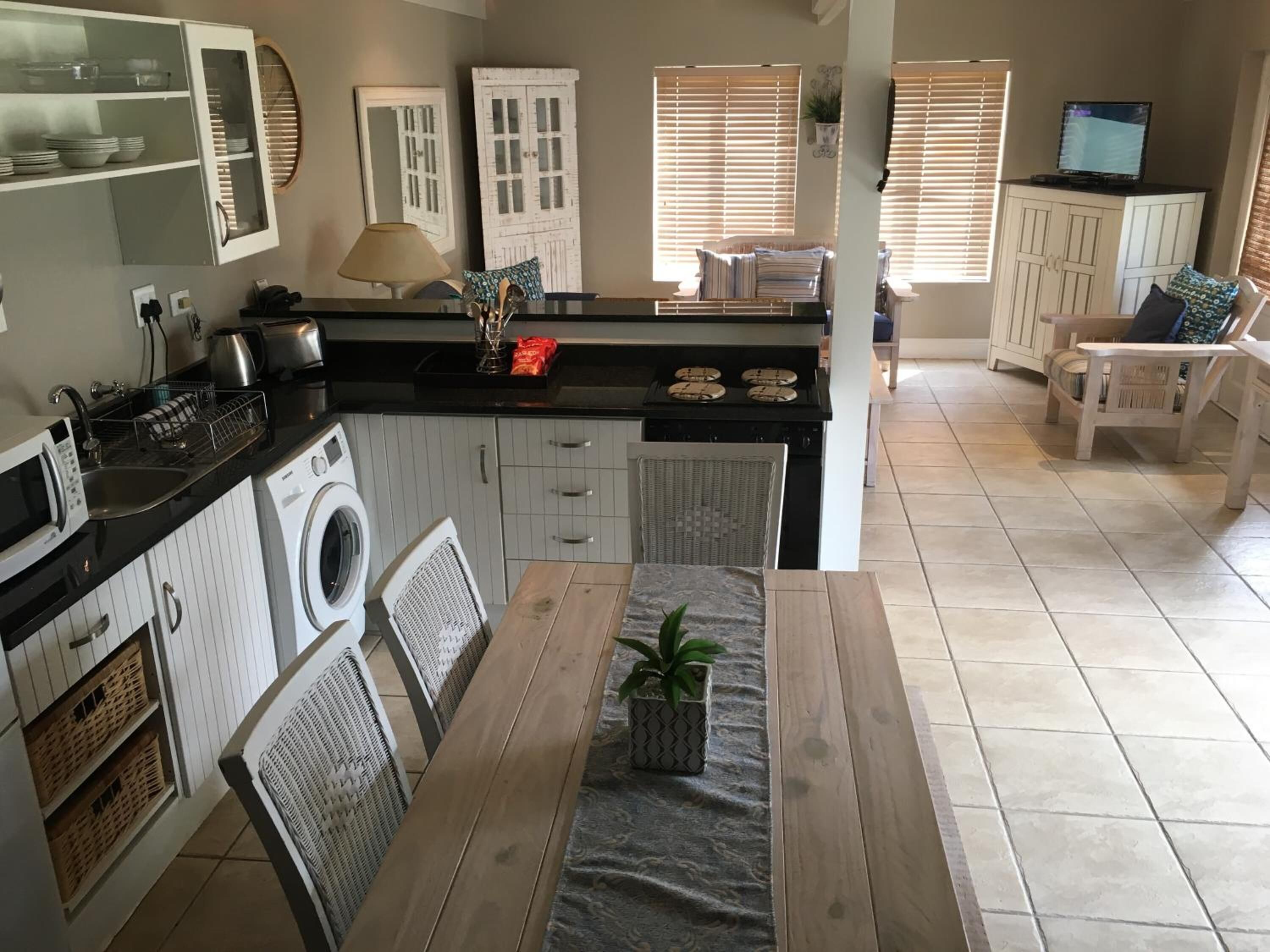 Een kleine keuken met een eethoek, een wasmachine en een televisie.