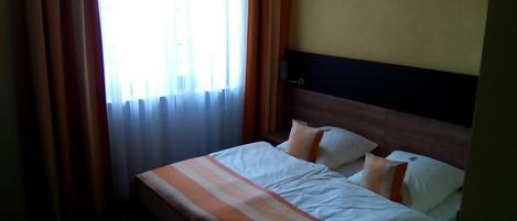 A hotel room with a bed, curtains, and a window.
