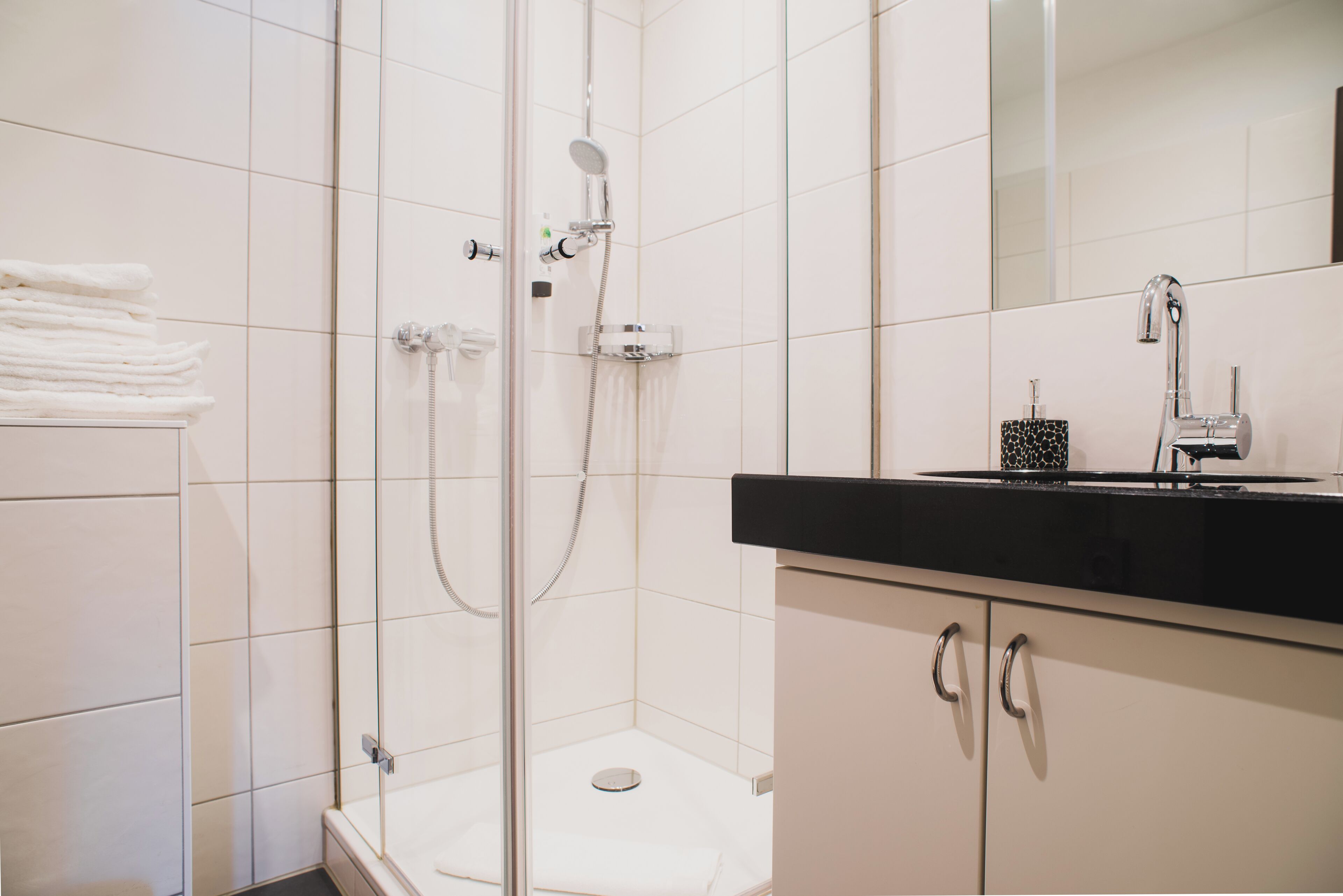 Un baño moderno con ducha de vidrio, inodoro y tocador con encimera negra.