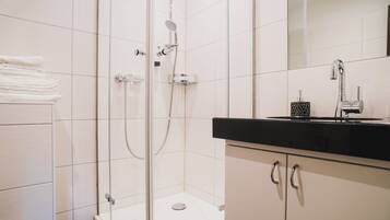 Un baño moderno con ducha de vidrio, inodoro y tocador con encimera negra.