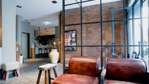 A modern interior with leather seating, a large vase, and a brick wall.