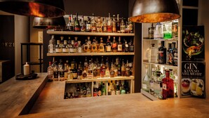 A bar area with shelves of liquor bottles, a candle, and a poster.