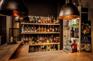 Una zona de bar con estantes llenos de botellas de licor, una vela y un cartel.