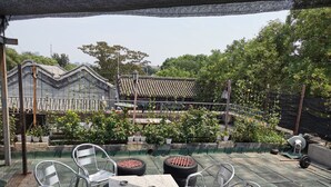 A patio area with a table and chairs, surrounded by potted plants and a view of traditional architecture in the background. - Beijing Downtown Travelotel (Beijing)