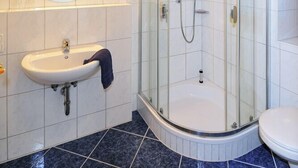 A modern bathroom with a glass-enclosed shower, a round mirror, and a white sink. - Gaestehaus Vogl (Berchtesgaden)