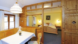 A wooden room with a bed, a table with a chair, and a large mirror. - Gaestehaus Vogl (Berchtesgaden)
