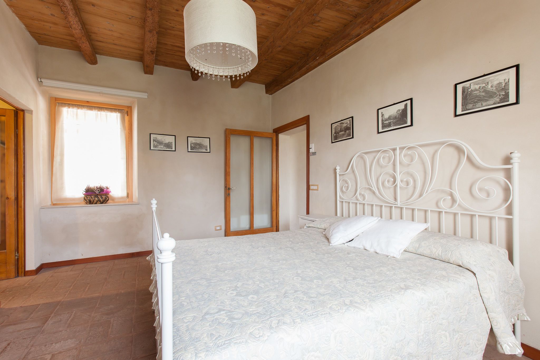 Une chambre à coucher avec un lit, un plafond en bois et une fenêtre avec des rideaux.