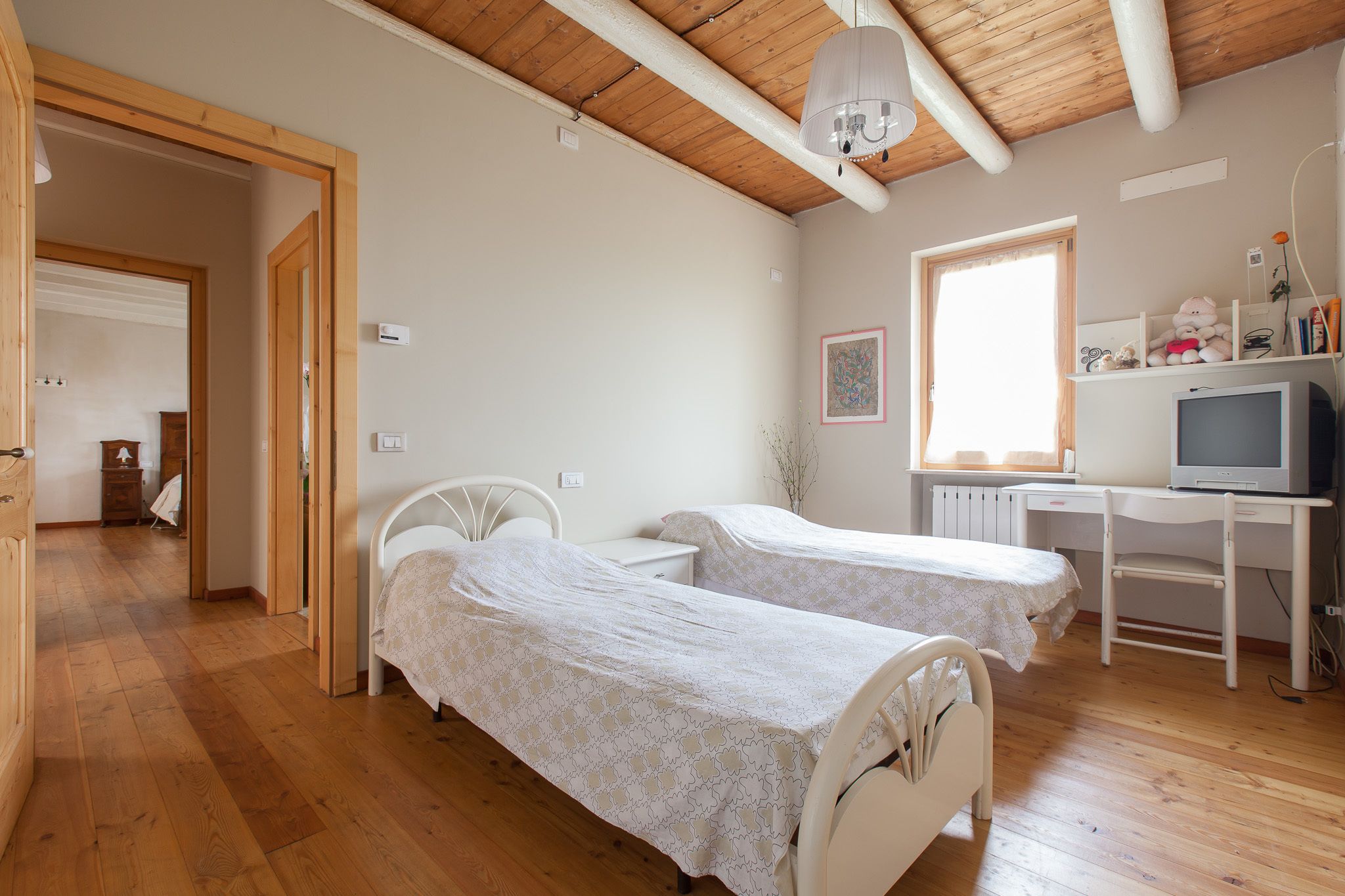 Ein Schlafzimmer mit zwei Betten, einem Schreibtisch mit Computer und einem Fenster.