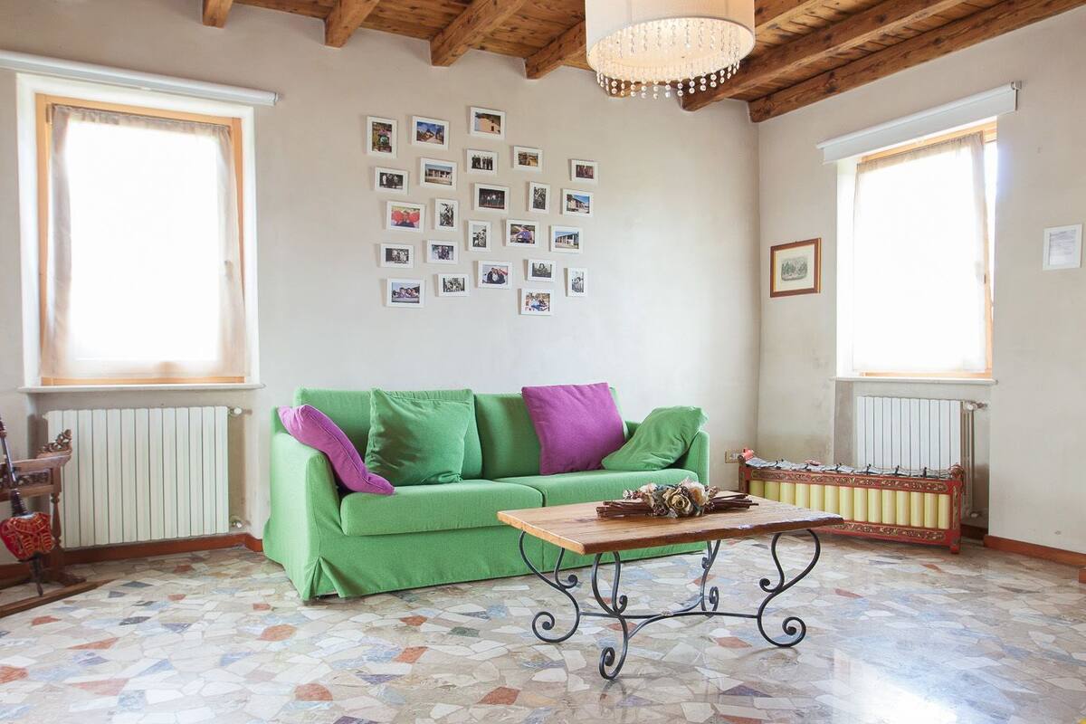 A spacious room with a green sofa, a wooden table, and a mosaic floor.