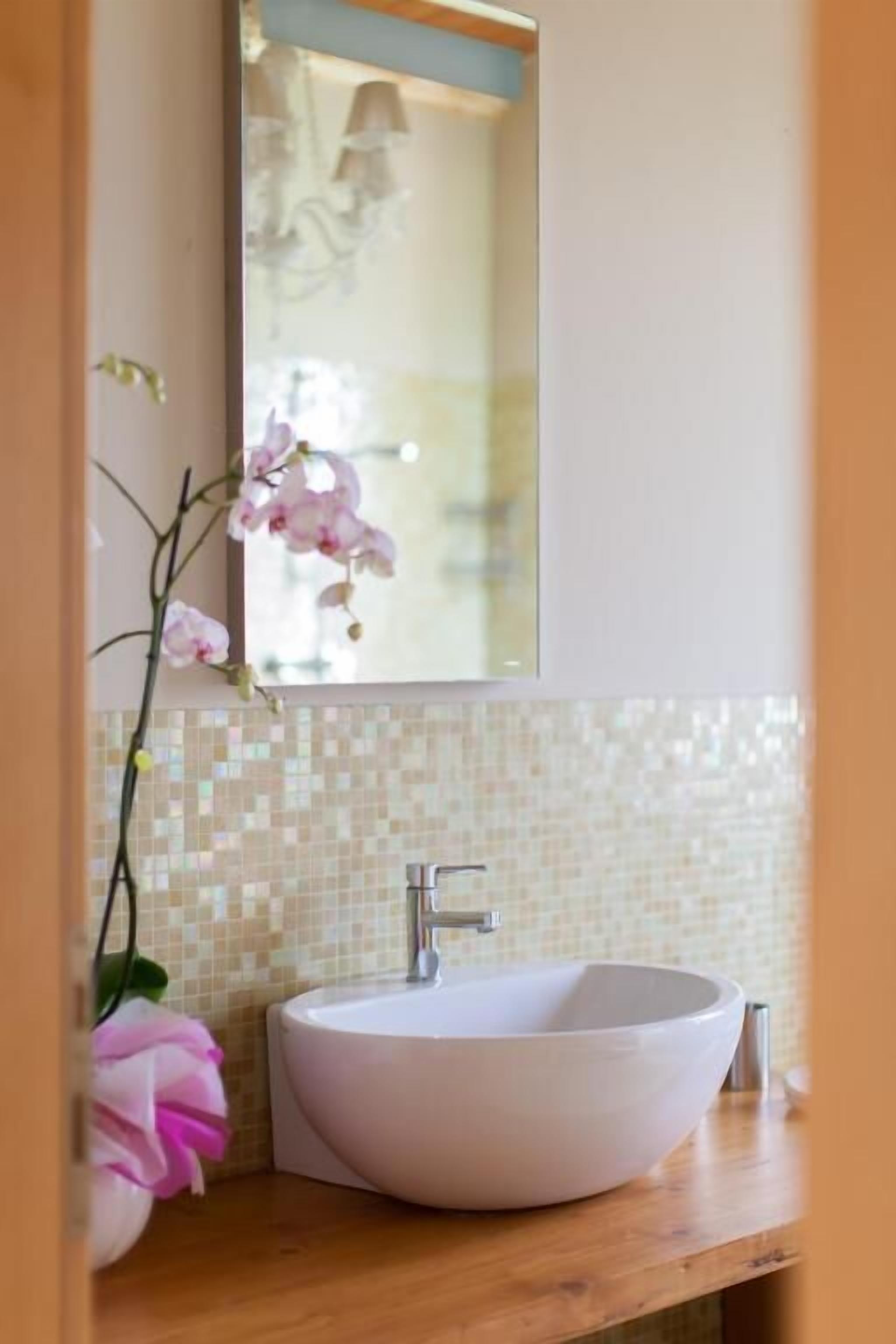 Un baño con un lavabo blanco, un espejo y un salpicadero de azulejos.