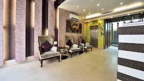 A reception area with a row of armchairs, a reception desk, and a wall-mounted air conditioning unit. - Hotel Taksh Inn (New Delhi)