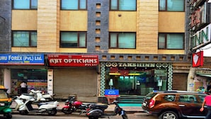 A multi-story building with a ground-level shop and a hotel entrance. - Hotel Taksh Inn (New Delhi)