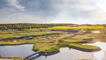 Un campo de golf con un puente, cuerpos de agua y vegetación circundante.