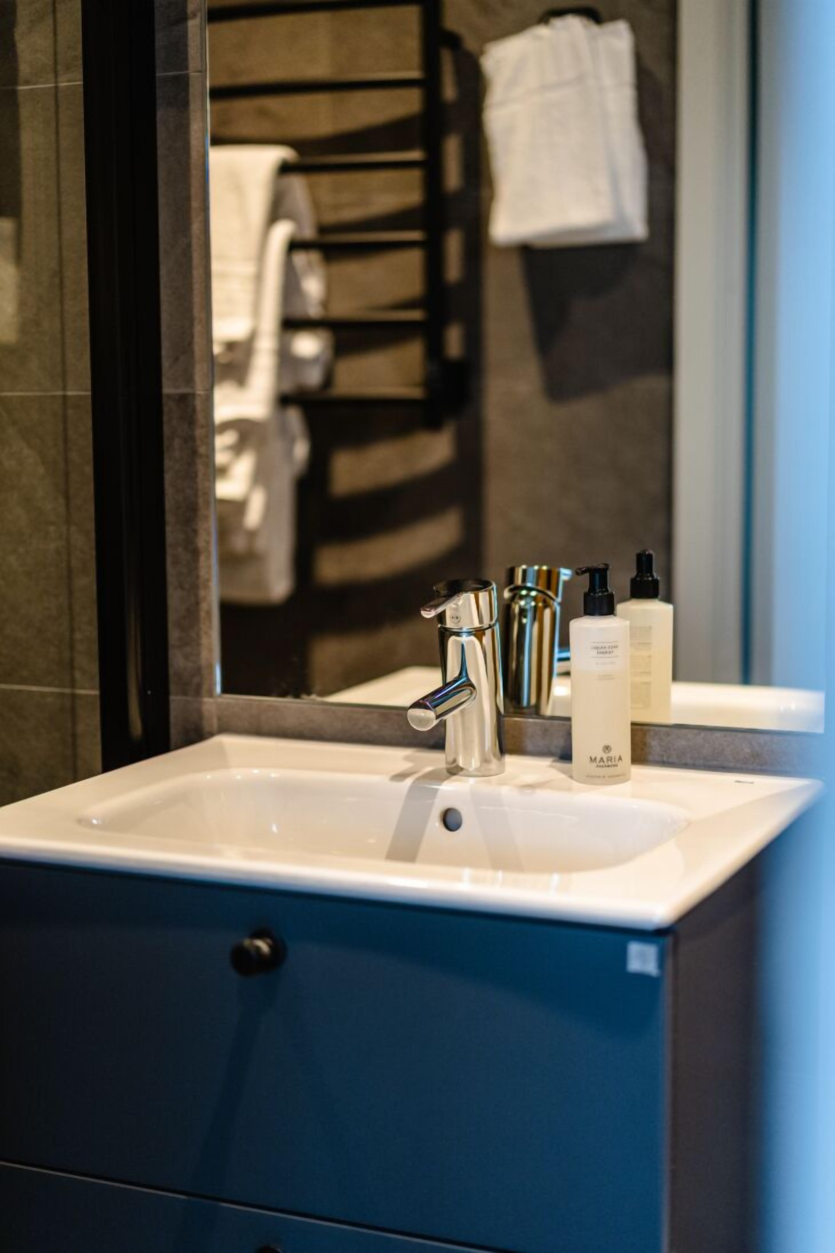 A bathroom with a white sink, a mirror, and toiletries on the counter.